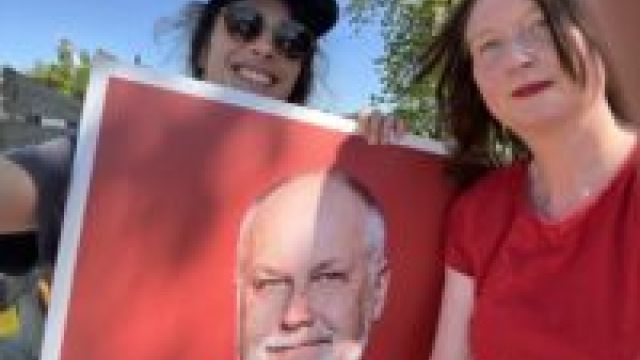 Två personer med en affisch med Jonas Sjöstedt på.